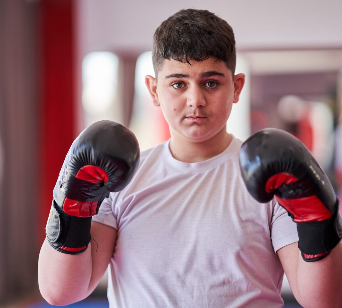 Confident overweight boxer with gloves posing in the gym